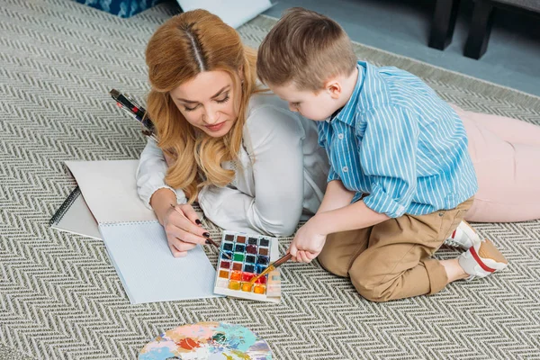 High angle view of mother and son dipping paintbrushes into paints — Stock Photo