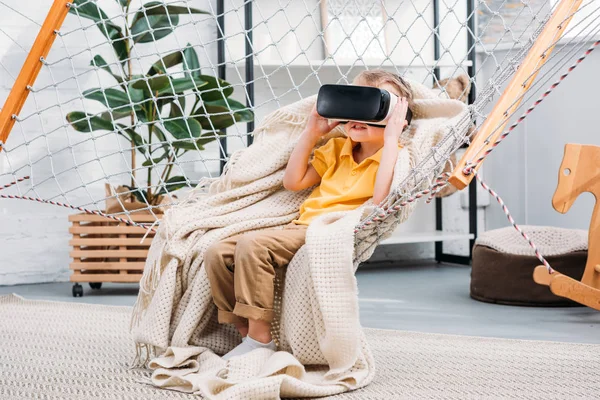 Niño en hamaca de cuerda con auriculares de realidad virtual - foto de stock