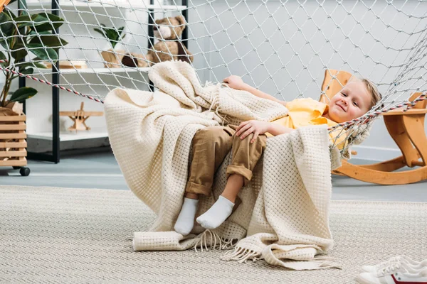 Улыбающийся мальчик, лежащий в веревочном гамаке — стоковое фото