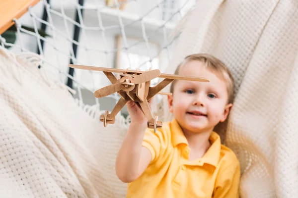 Мальчик играет с деревянной игрушкой для самолета — стоковое фото