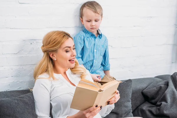 Lächelnde Mutter liest kleinen Jungen Buch vor — Stockfoto