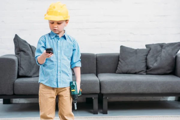 Petit garçon dans un casque de sécurité tenant des outils — Photo de stock