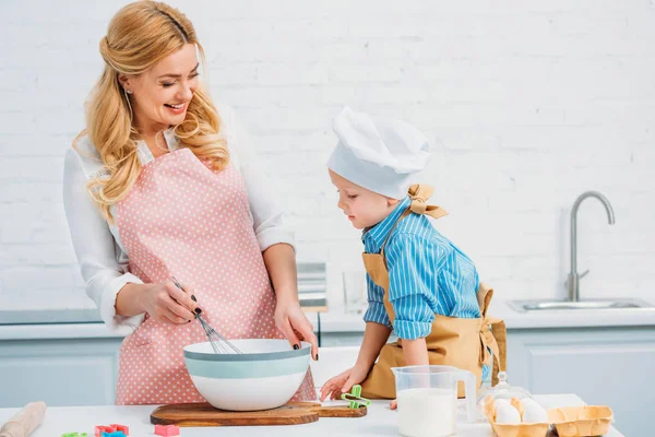 Улыбающиеся мать и сын на кухне готовят вместе — стоковое фото