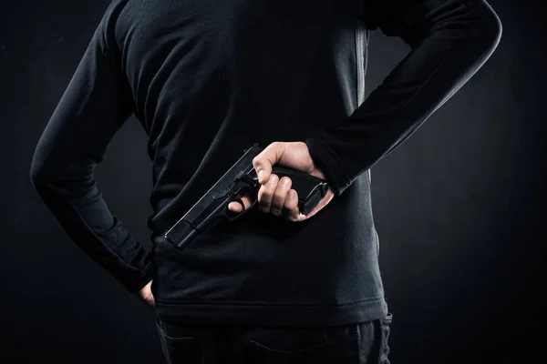 Вид ззаду гармати в руках гангстера на чорному — стокове фото