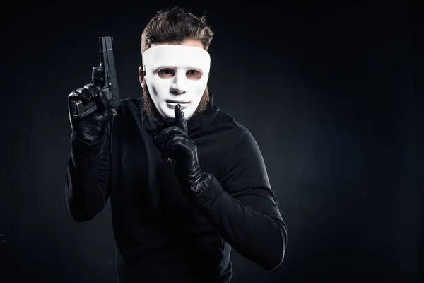 Thief in mask holding gun and showing silence gesture — Stock Photo