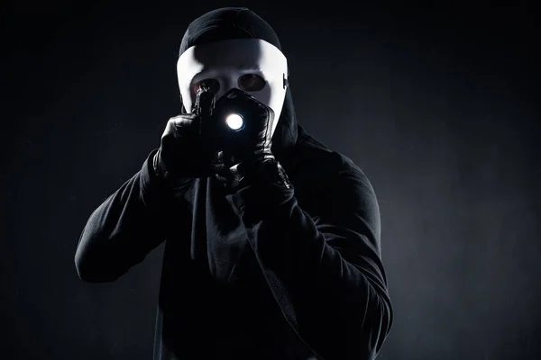 Cambrioleur en masque et cagoule visant avec pistolet et lampe de poche — Photo de stock