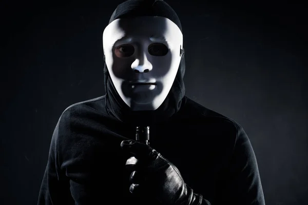 Грабитель в белой маске держит фонарик — стоковое фото