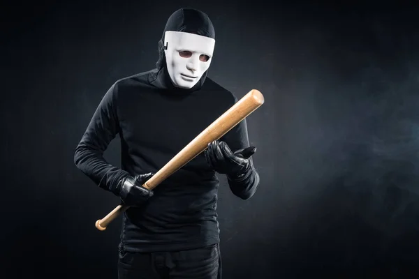 Criminal en máscara y pasamontañas sosteniendo bate de béisbol - foto de stock