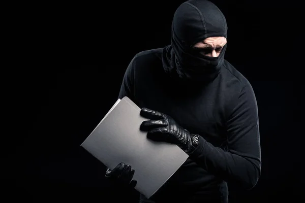 Criminal in balaclava holding confidential documents — Stock Photo