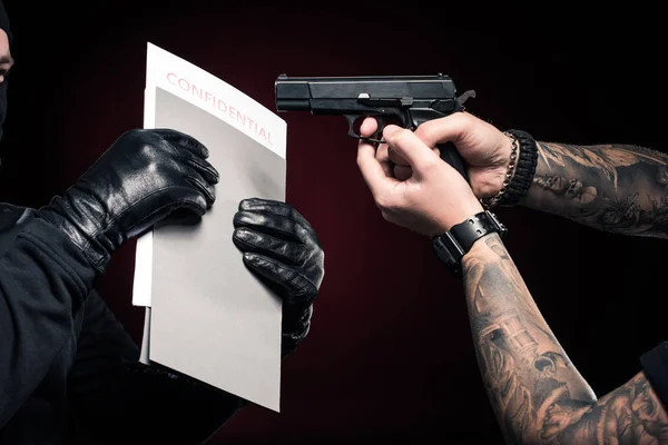 Man with gun protecting his confidential papers from robber — Stock Photo