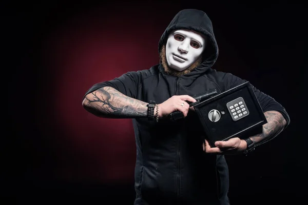 Burglar in mask holding gun and locked safe — Stock Photo