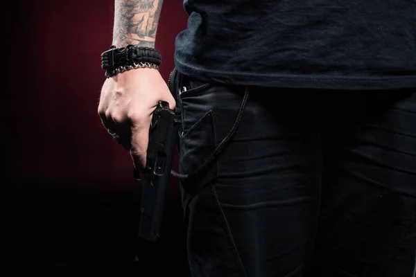 Крупним планом зброя в чоловічій руці на червоному тлі — стокове фото