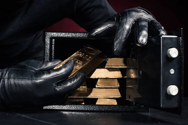 Cropped view of thief stealing gold ingots from safe — Stock Photo