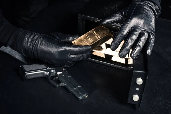 Vista de perto do ladrão com arma tomando barras de ouro de cofre — Fotografia de Stock