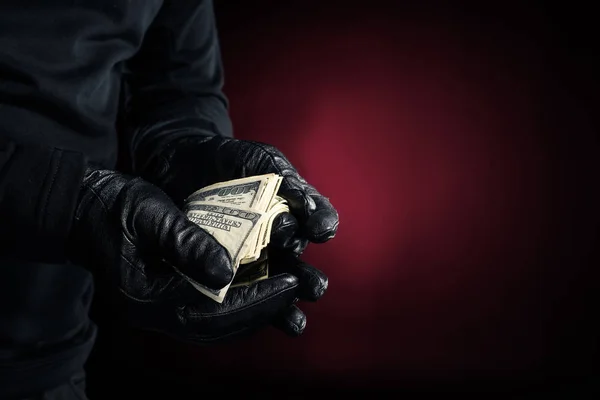 Hombre con guantes negros sosteniendo billetes de dólar - foto de stock