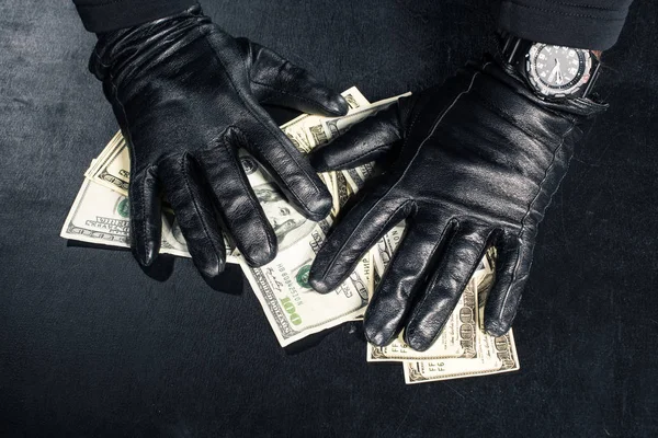 Mains masculines en gants noirs saisissant des dollars — Photo de stock