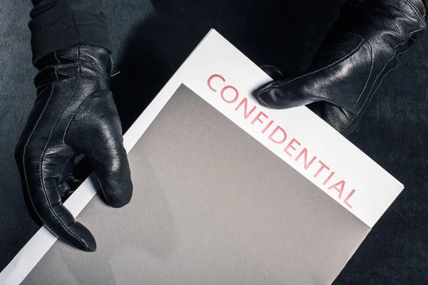 Close-up view of criminal holding folder with confidential documents — Stock Photo