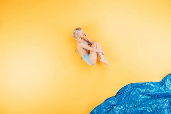 Молода жінка в купальнику стрибає в уяві море на жовтому — стокове фото
