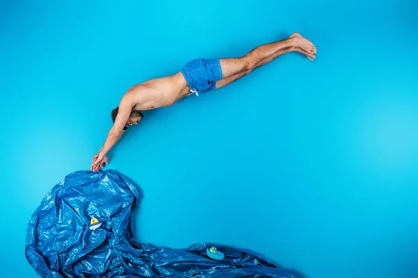Giovane in pantaloncini immersioni in immaginare mare con barche giocattolo su blu, concetto di vacanza estiva — Foto stock