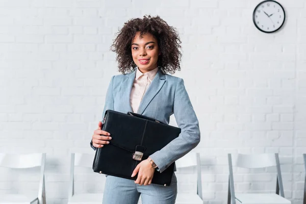 Mujer de negocios afroamericana en traje con maletín - foto de stock