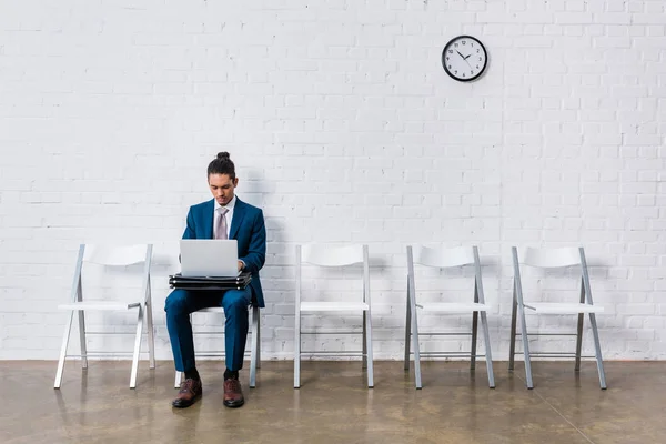 Empresario trabajando en el ordenador portátil mientras está sentado en la silla - foto de stock