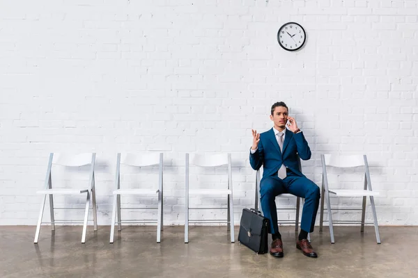 Businessman talking on phone while sitting and waiting on chair — Stock Photo