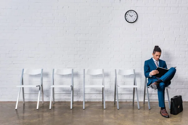 Hombre leyendo papeles mientras está sentado en la silla - foto de stock