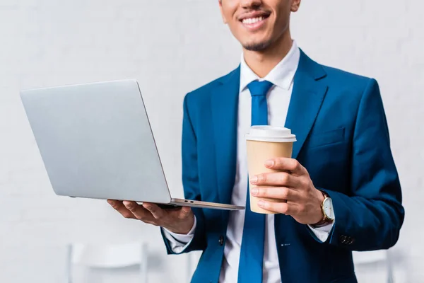 Hombre de negocios afroamericano sosteniendo portátil y taza de café - foto de stock