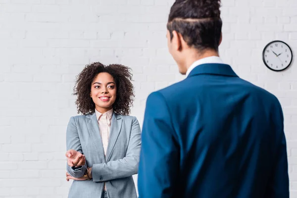 Femme d'affaires afro-américaine parlant à un homme d'affaires sur fond de mur blanc — Photo de stock