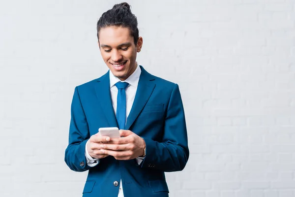 Homme d'affaires afro-américain utilisant un smartphone sur fond blanc — Photo de stock