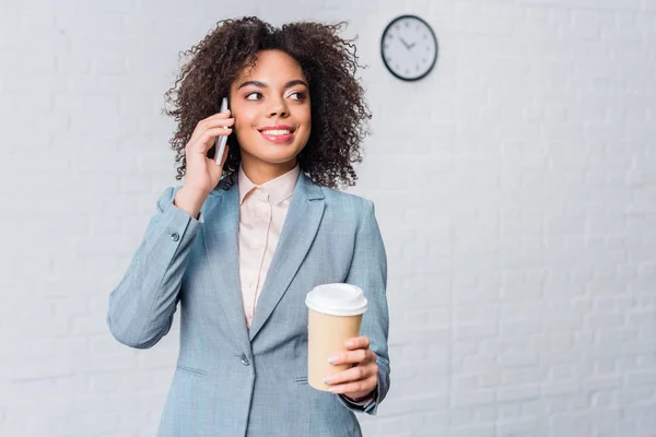 Mujer de negocios afroamericana con taza de café hablando por teléfono - foto de stock