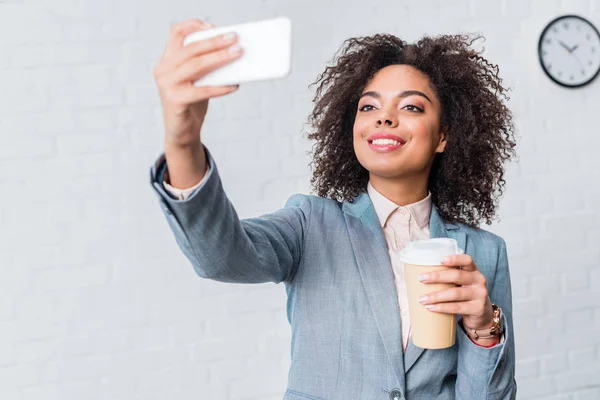 Femme d'affaires afro-américaine avec tasse à café prenant selfie — Photo de stock
