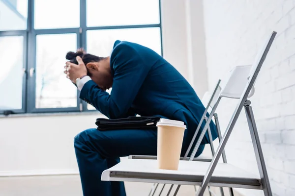 Hombre de negocios estresado sentado en la silla por taza de café - foto de stock