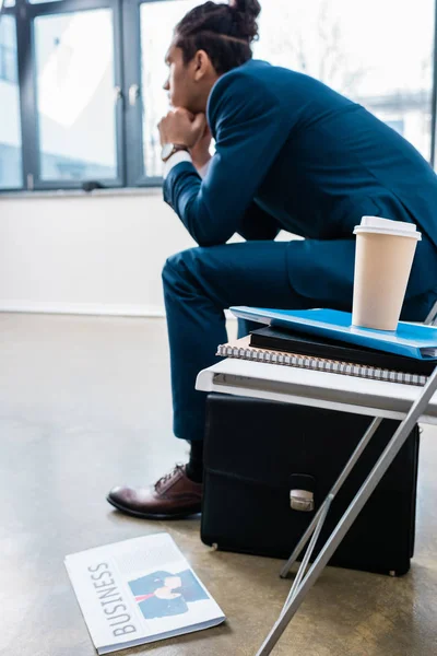 Businessman sitting on chair and waiting by stack of documents and coffee cup — Stock Photo