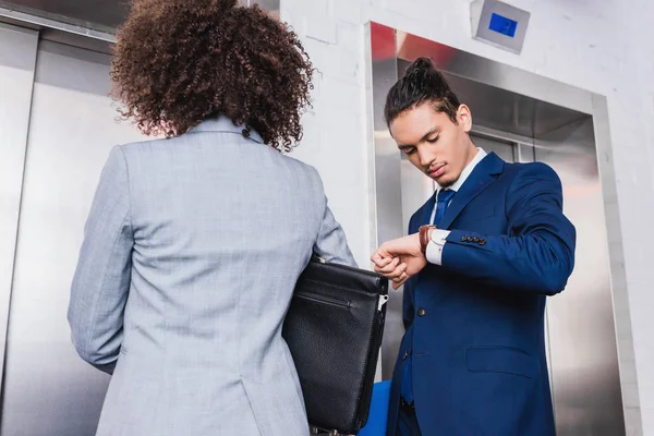 Afrikanischer amerikanischer Geschäftsmann überprüft seine Uhr und wartet auf Aufzug — Stockfoto