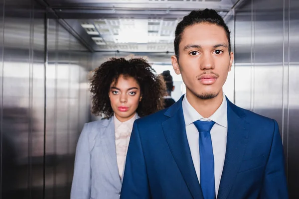 Afroamericano uomo d'affari e donna d'affari in piedi in ascensore — Foto stock