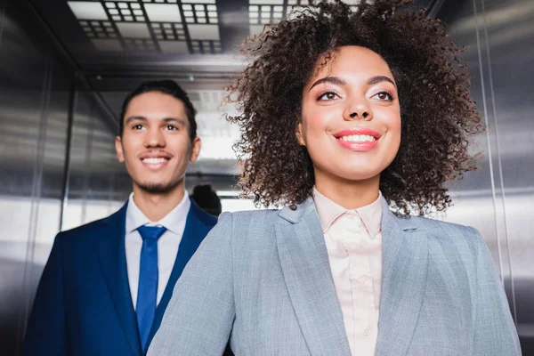 Empresários afro-americanos sorridentes montando um elevador — Fotografia de Stock