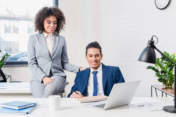 Empresario y mujer de negocios mirando portátil en la mesa de la oficina - foto de stock