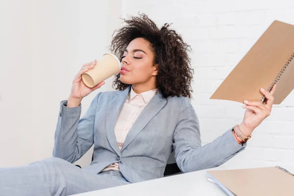 Africano americano mulher segurando notepad e beber café — Fotografia de Stock