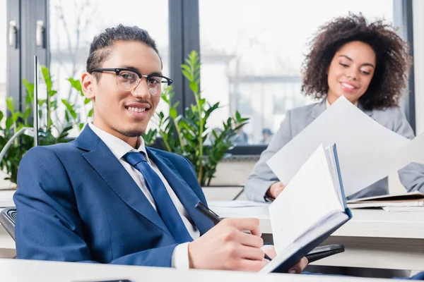 Uomo d'affari che scrive nel quaderno in carica da donna d'affari che lavora — Foto stock