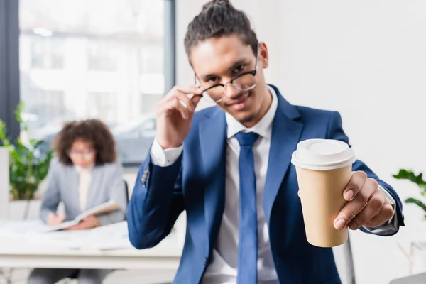 Uomo d'affari sorridente che offre caffè in tazza di carta — Foto stock