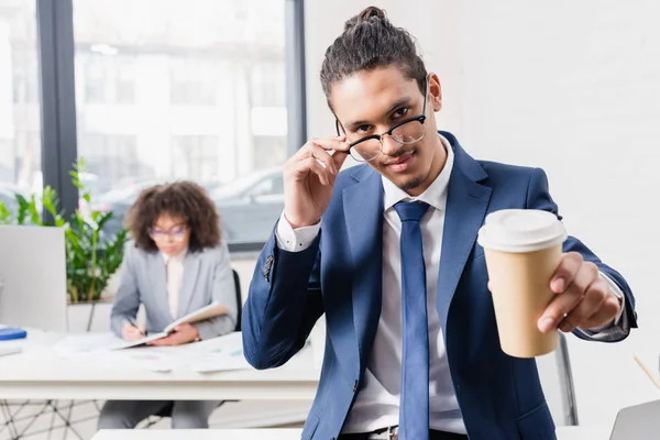 Uomo d'affari afroamericano in occhiali che tiene il caffè per andare — Foto stock