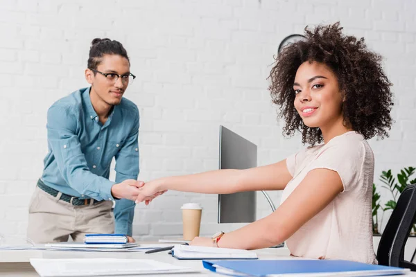 Empresária apertando a mão de homem por mesa com computador — Fotografia de Stock