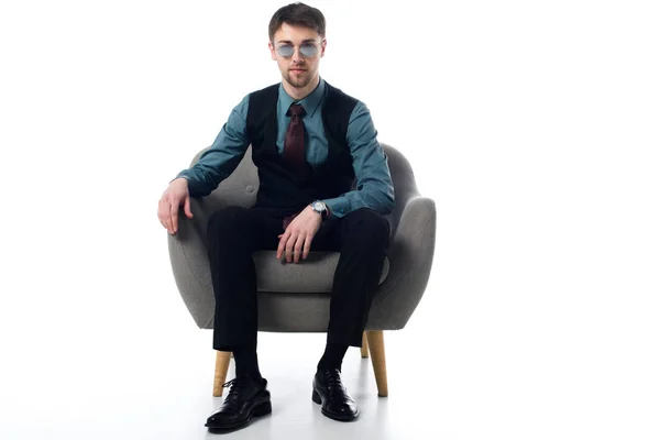 Elegante espía en gafas de sol sentado en sillón aislado en blanco - foto de stock