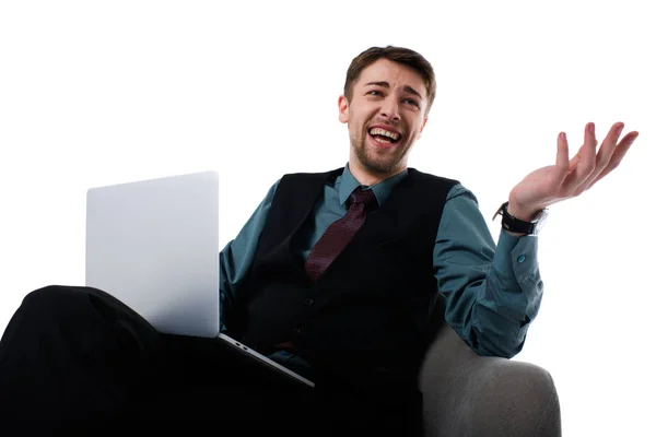 Retrato de agente alegre con portátil sentado en sillón y mirando hacia otro lado aislado en blanco - foto de stock
