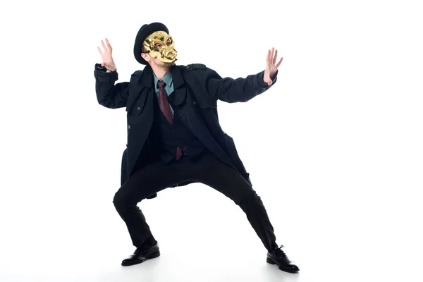 Criminal en máscara, sombrero y abrigo negro posando aislado sobre blanco - foto de stock
