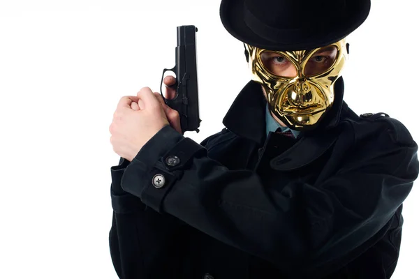 Porträt des Verbrechers mit goldener Maske, Hut und schwarzem Mantel mit Pistole in den Händen, der isoliert auf weiß in die Kamera blickt — Stockfoto