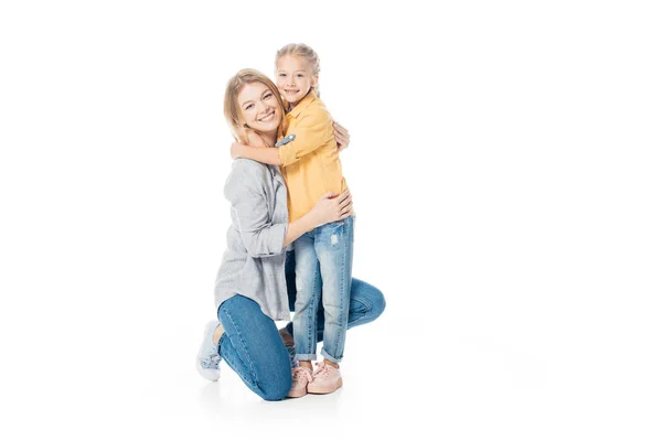 Mãe feliz e filha bonita olhando para a câmera enquanto abraçando uns aos outros isolado no branco — Fotografia de Stock