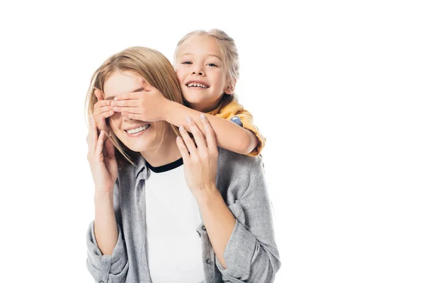 Porträt eines entzückenden Kindes, das die Augen seiner Mutter bedeckt, um sie isoliert auf Weiß zu überraschen — Stockfoto