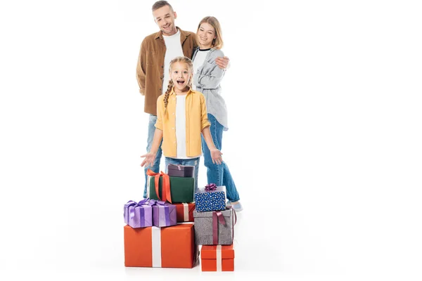 Excited kid with pile of wrapped gifts and parents behind isolated on white — Stock Photo